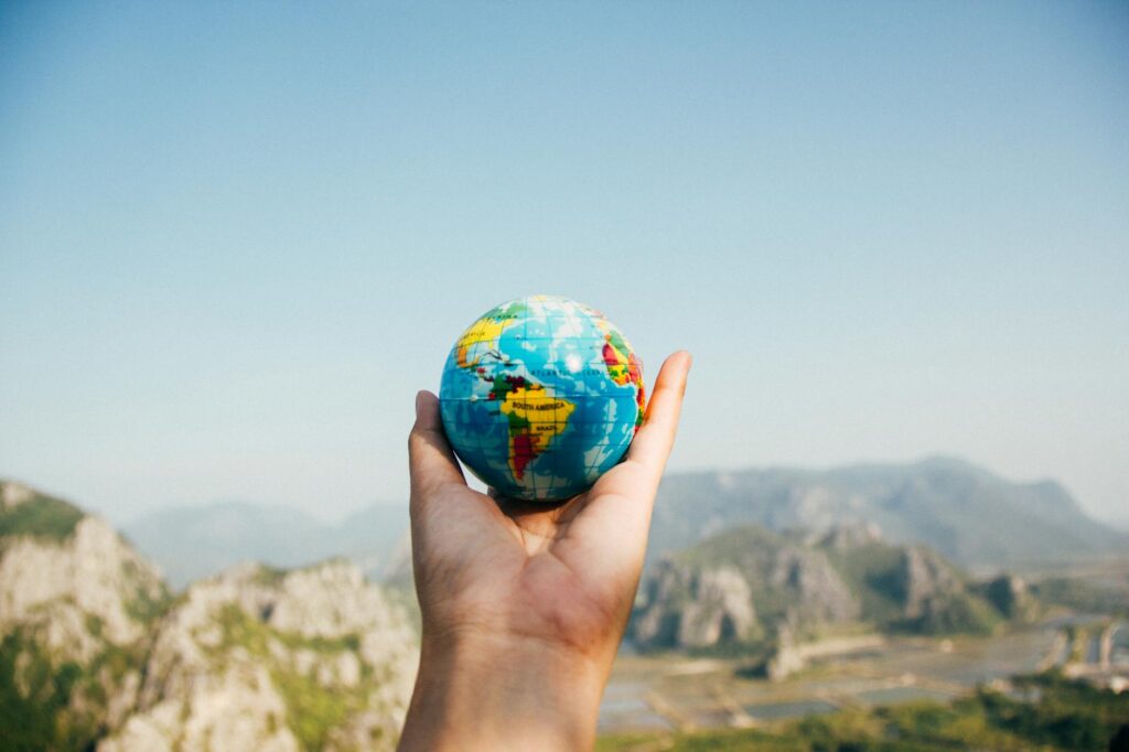 person holding world globe facing mountain