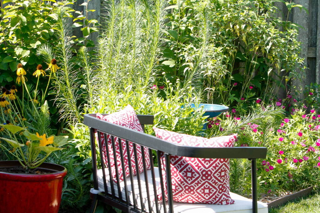 Outdoor bench with throw pillows for enjoying a beautifully landscaped native garden in Springfield, Missouri